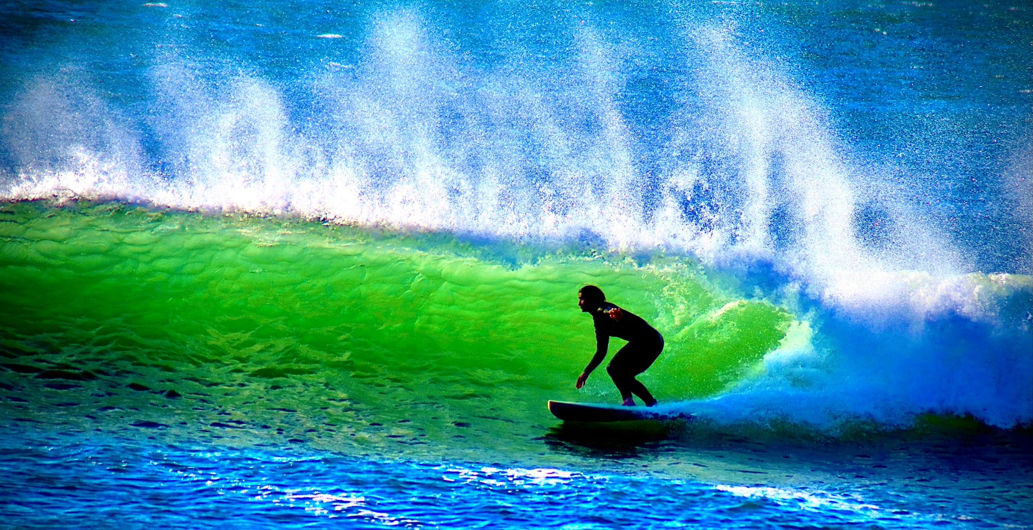 Surfer in a glowing green barrel wave